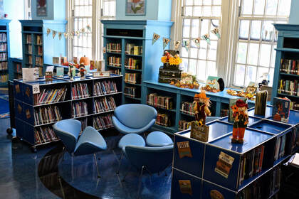 Reading area with cushioned chairs and footstools in school library.